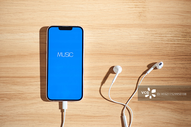 桌面上一台插有耳机的智能手机图片素材