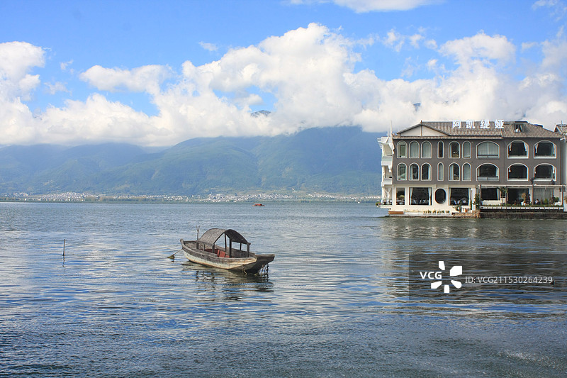 大理双廊在多云的天空中看洱海上的船只和岸边的建筑景观图片素材