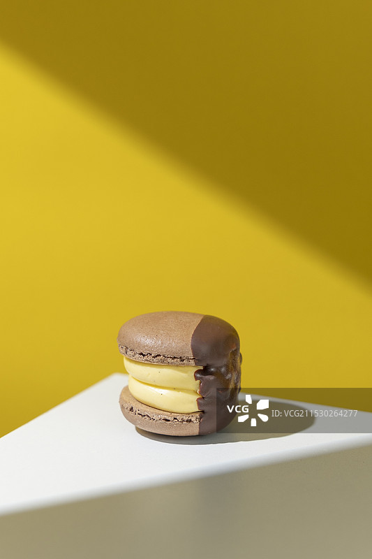 白桌黄色背景光下的香草巧克力马卡龙胖卡龙图片素材
