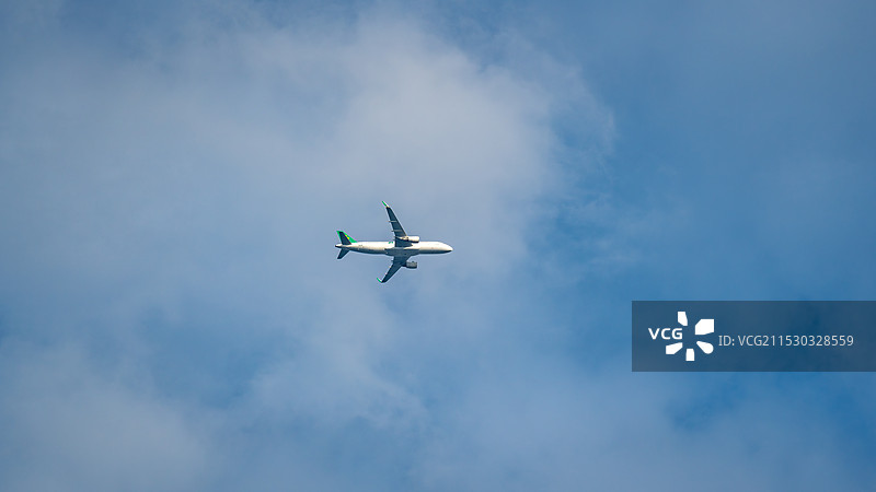 旅途中的商用飞机客机在蓝天下飞行的低角度视图图片素材