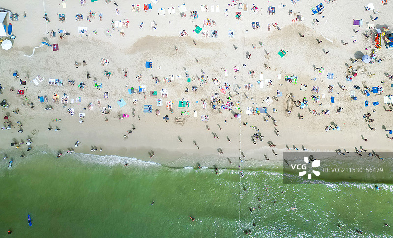海南省三亚市大东海旅游区冬季沙滩海岸线上密密麻麻度假的中国与外国游客图片素材