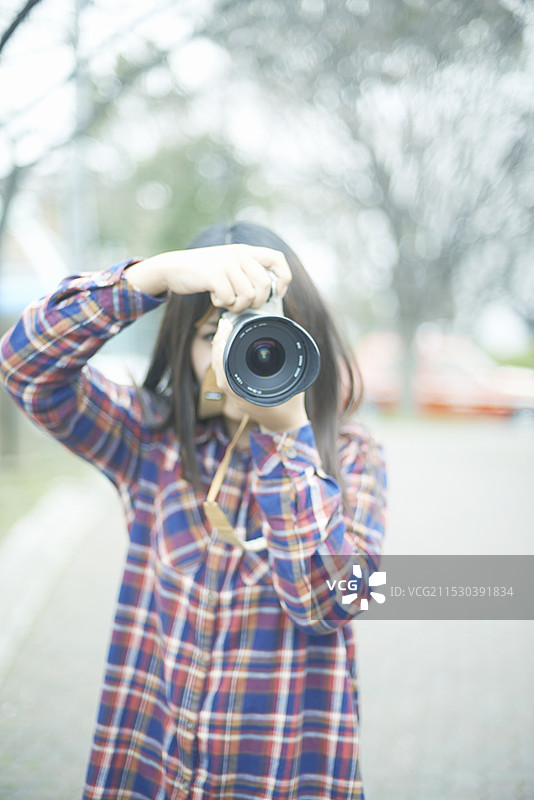年轻女性手持相机拍摄图片素材