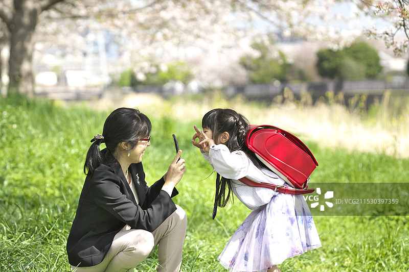 母亲为一年级的小学生拍照图片素材