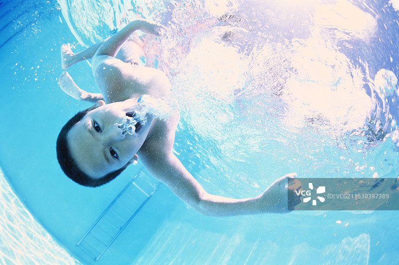 男孩在游泳池里游泳图片素材