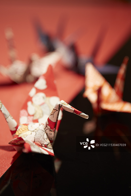 几只用千代纸折叠的鹤放在红白色的托盘上图片素材