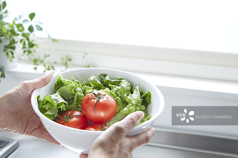 女人的手在厨房里拿着装有蔬菜的碗图片素材