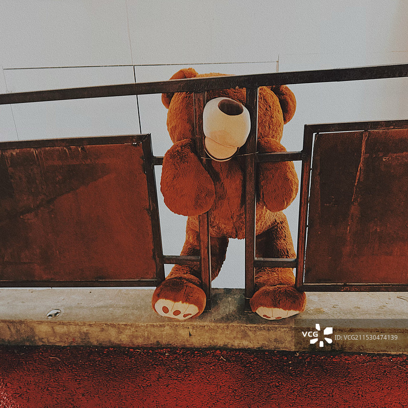 挤在栏杆里的熊玩偶图片素材