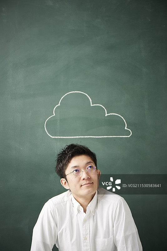 一个人在黑板前思考，黑板上写着云朵。图片素材