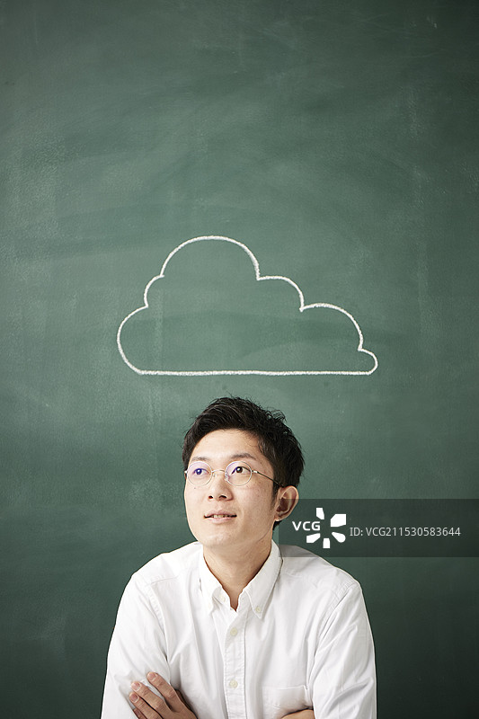 一个人在黑板前思考，黑板上写着云朵。图片素材