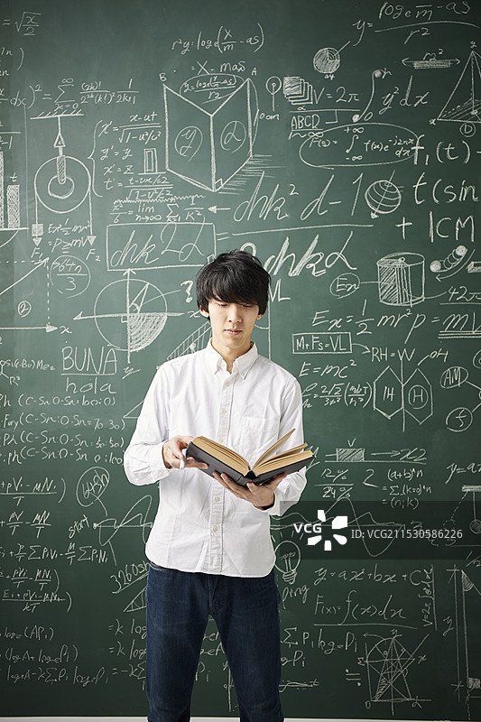 在黑板前阅读一本书图片素材