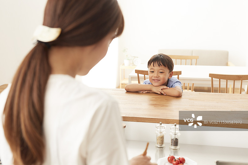 男孩在厨房与正在制作便当的女人面对面聊天图片素材