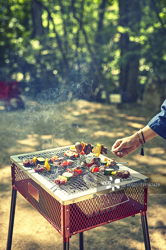 女人在炭火烧烤架上烤制烧烤串图片素材