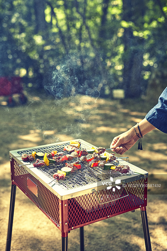 女人在炭火烤架上烤烧烤串图片素材