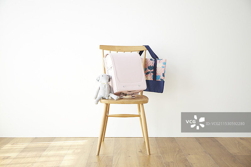 墙前的椅子上放着书包图片素材