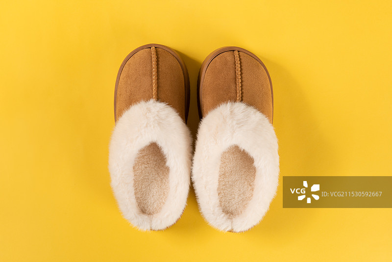 黄色背景上的一双毛绒棉拖鞋图片素材