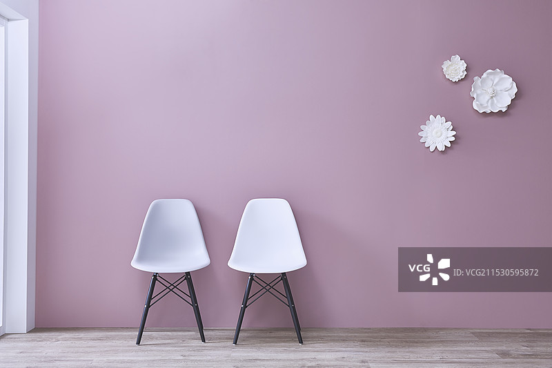 白色和灰色的椅子以及白色花卉装饰放置在粉色墙壁前面图片素材