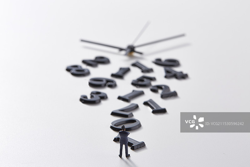 微型玩偶站在不连贯的数字和钟表指针前图片素材