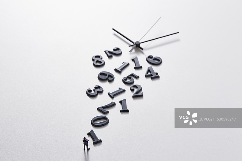 微型玩偶站在不连贯的数字和时钟指针前面图片素材