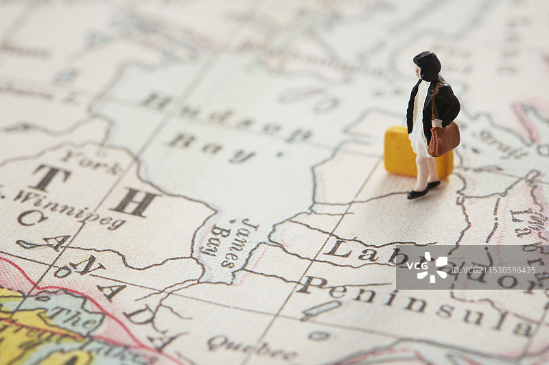 手持行李箱的小型女性站在世界地图上图片素材