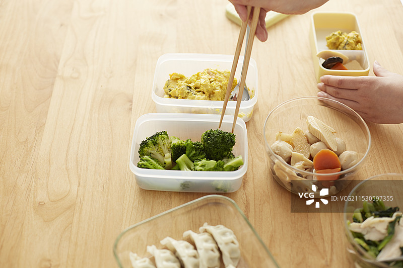 女人将食物装入保鲜盒中放入午餐盒里图片素材