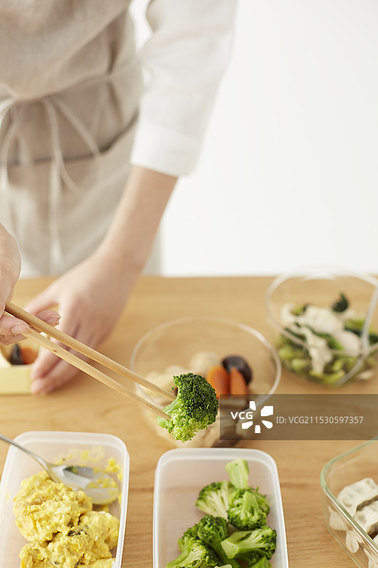 女人将食物装入保鲜盒中放入午餐盒里图片素材