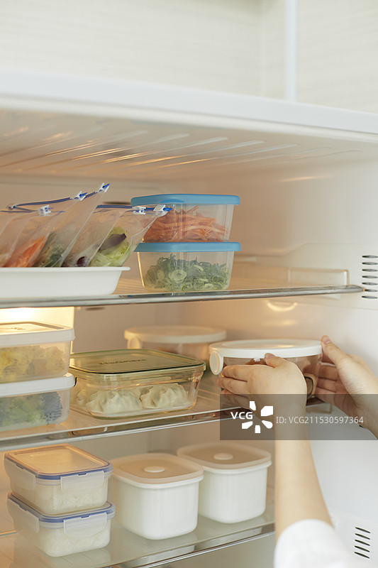 人们的手从冰箱中拿出保鲜盒图片素材
