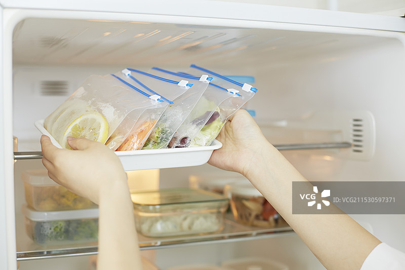 从冰箱中取出储存袋里小份食物的人图片素材