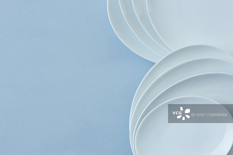 叠放的白色盘子与浅蓝色背景图片素材