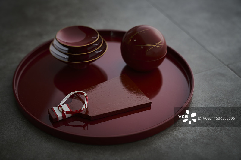 一个红色圆盘上的杯子，一个羽毛形状的盘子和一个带有水引的圆形容器图片素材