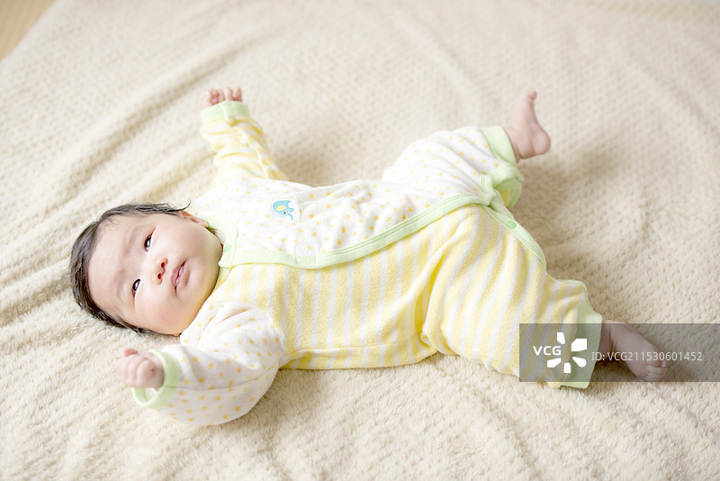 三个月大的宝宝正在用力地挥动手臂和腿。图片素材