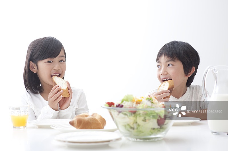 孩子们和一位男士及女士在餐桌上吃早餐图片素材