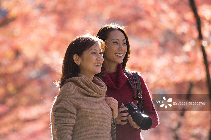 母女俩享受秋天观赏落叶的乐趣图片素材