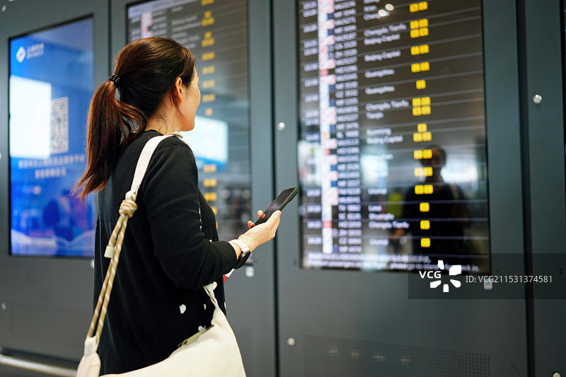 一名女子在机场用智能手机和机票查看航班信息图片素材