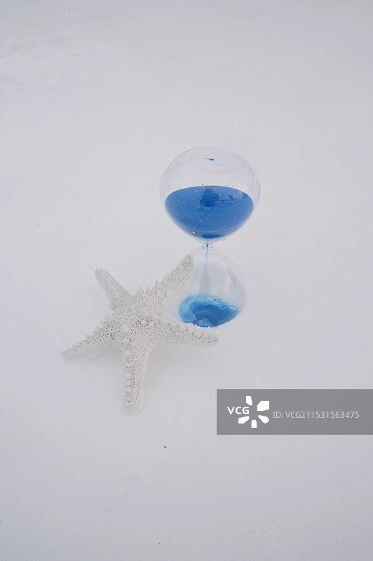 雪地里的蓝色玻璃沙漏与白色海星图片素材