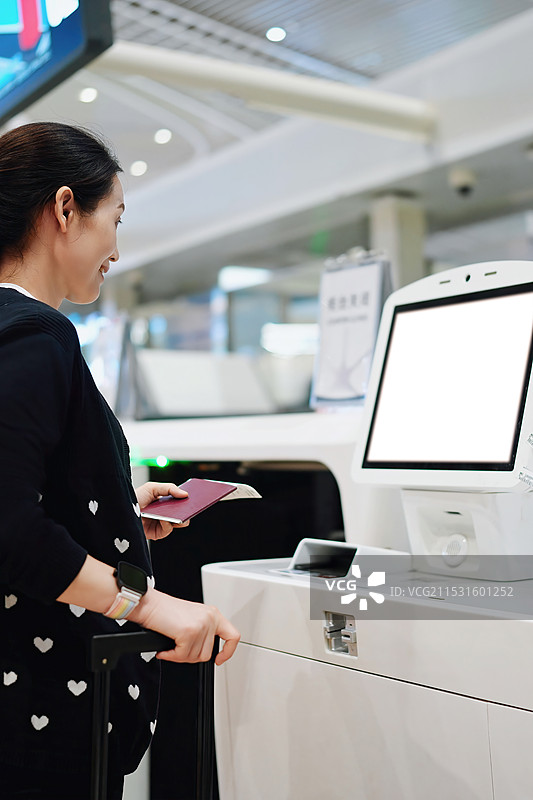 微笑的旅客在现代机场使用自助值机亭图片素材
