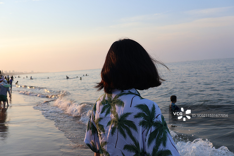 海南岛海口西秀海滩的傍晚穿着岛服的游客玩水图片素材