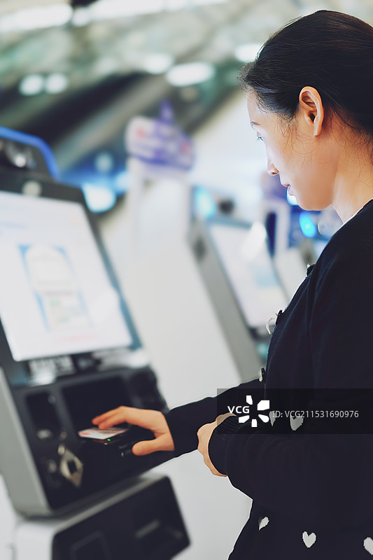 在机场使用自助服务亭办理登机手续的女性图片素材