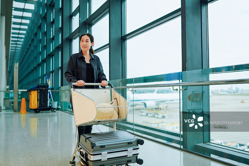 在机场航站楼提着行李车的女人，轻松旅行图片素材