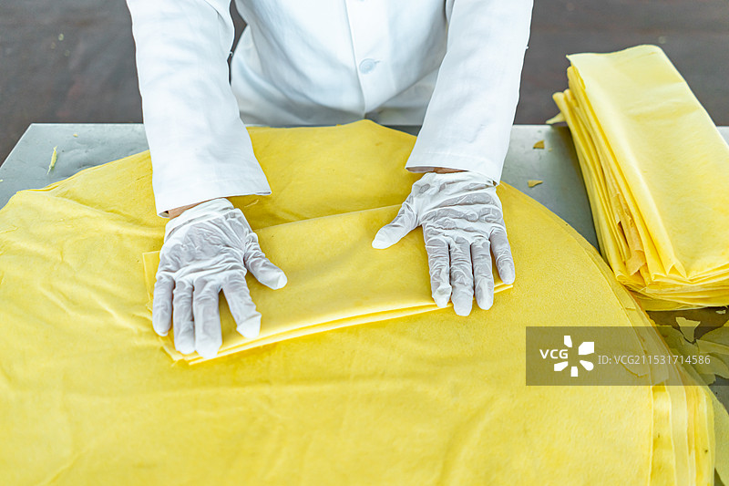 中国餐饮行业饮食产业，传统经典中国食品拍摄主题，工人正在叠新鲜出炉的山东小米玉米煎饼，室内无人图像图片素材