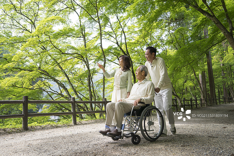 父亲和中年夫妇在轮椅上享受森林浴图片素材
