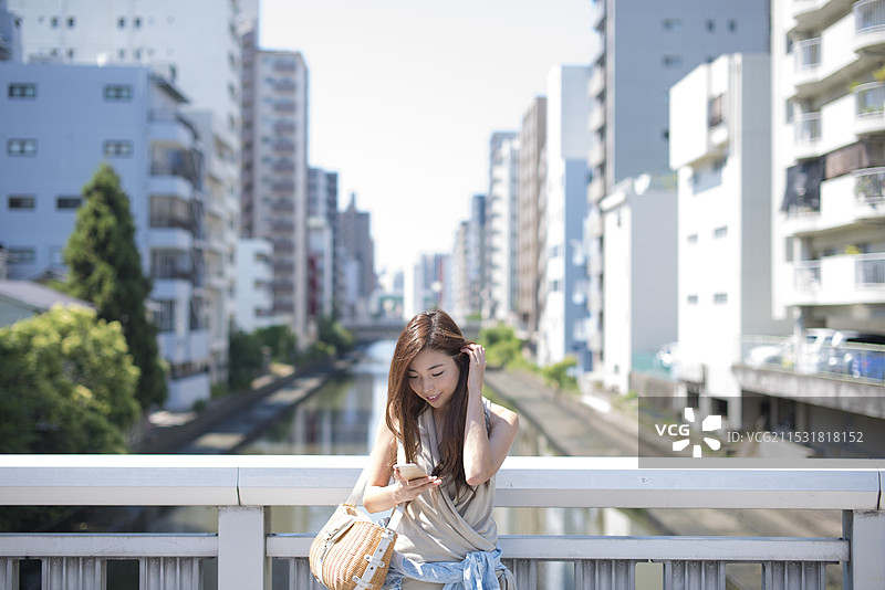在运河街道和桥上站着的女人，手里拿着手机图片素材
