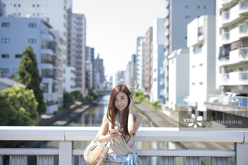 在运河街道和桥上站着的女人，手里拿着手机图片素材