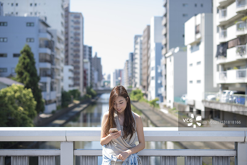 在运河街道和桥上站着的女人，手里拿着手机图片素材