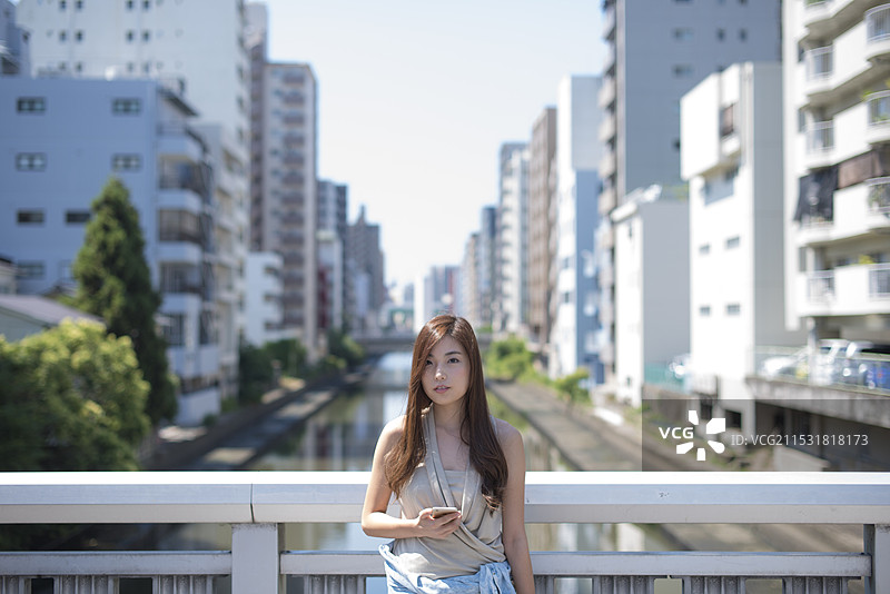 在运河街道和桥上站着的女人，手里拿着手机图片素材