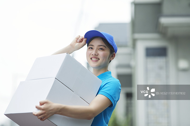 微笑的年轻女性穿着工作服，背负着重物图片素材