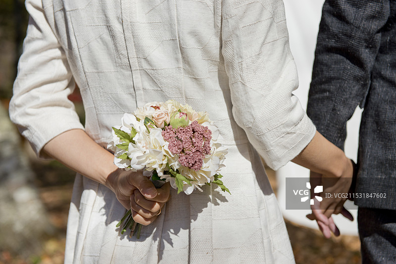 情侣手牵手走着，手中捧着花束图片素材