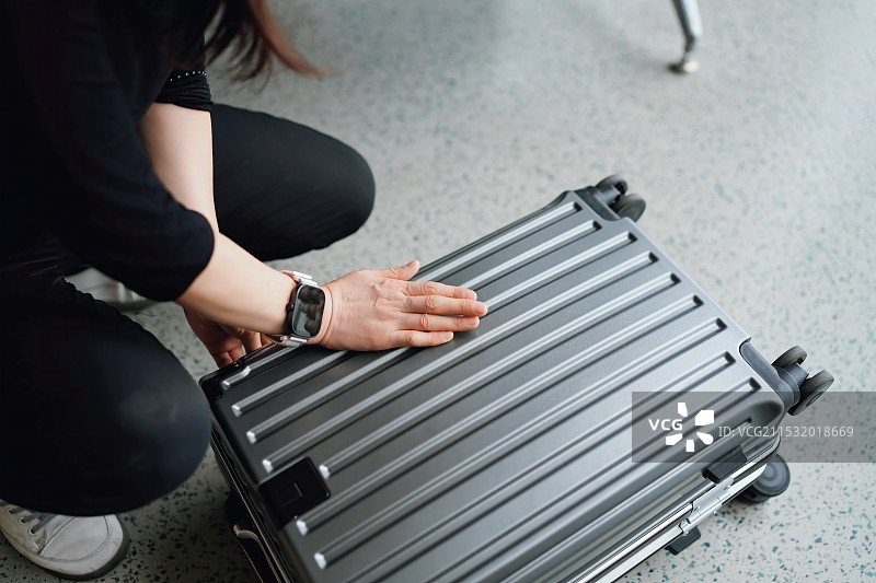 个性化旅行：一位女士检查她的银色行李图片素材