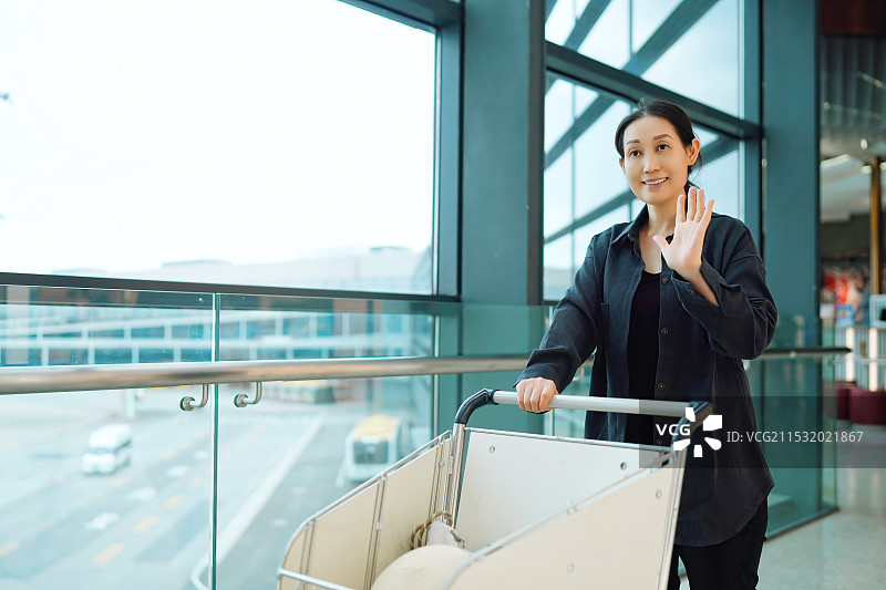 机场航站楼行李车上的快乐女人图片素材