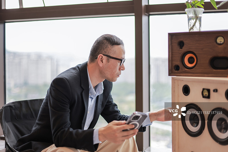 一位商务人士在办公室用手机连接蓝牙音响图片素材