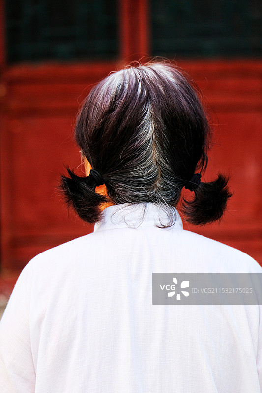 红色背景下老奶奶的背影图片素材